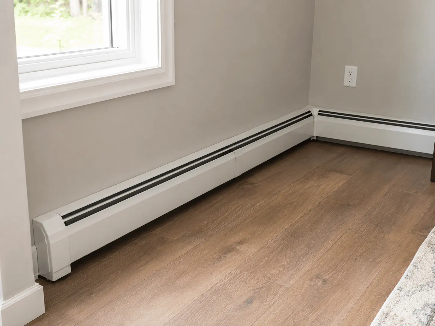 Electric baseboard heaters installed along the walls of a finished room